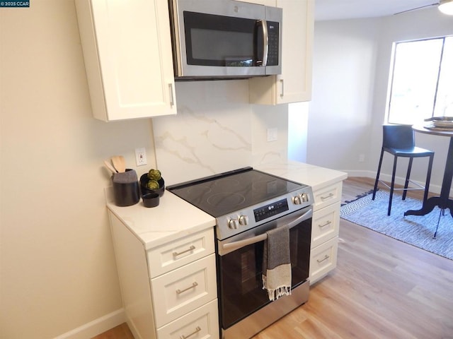 kitchen featuring light stone counters, stainless steel appliances, light hardwood / wood-style floors, and white cabinets