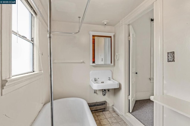 bathroom featuring sink, a bathtub, and baseboard heating