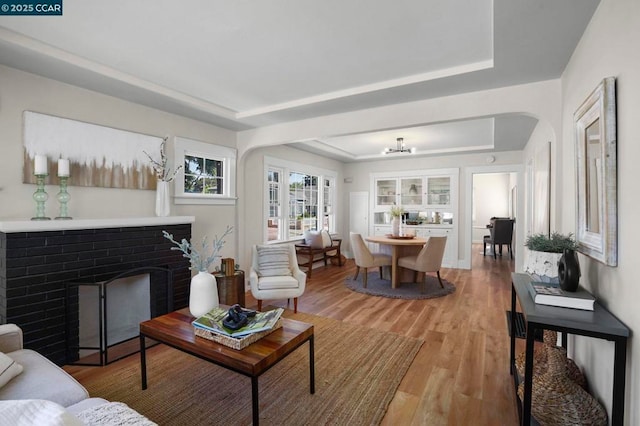 living room featuring hardwood / wood-style floors, a fireplace, and a tray ceiling