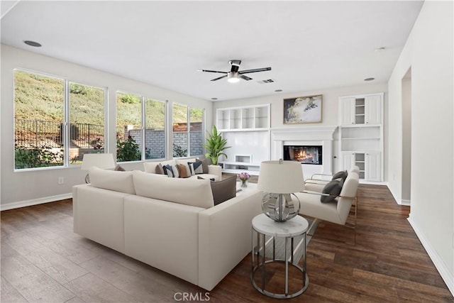 living room featuring ceiling fan, built in features, and dark wood-type flooring