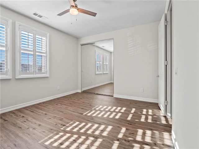 unfurnished bedroom featuring ceiling fan, a closet, and hardwood / wood-style flooring