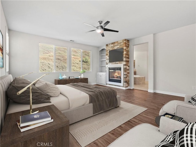 bedroom featuring ensuite bathroom, ceiling fan, hardwood / wood-style flooring, and a fireplace