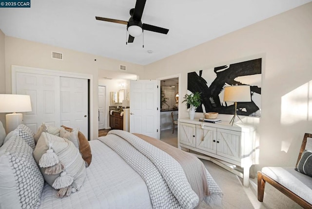 bedroom with ceiling fan, connected bathroom, a closet, and light carpet