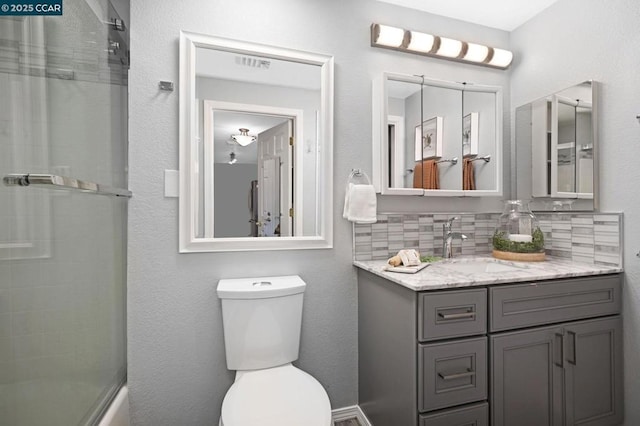 full bathroom featuring toilet, combined bath / shower with glass door, decorative backsplash, and vanity