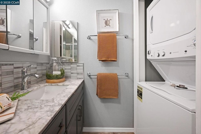 bathroom featuring backsplash, vanity, and stacked washer and dryer