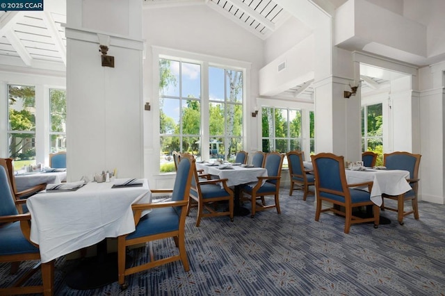 carpeted dining room featuring a towering ceiling