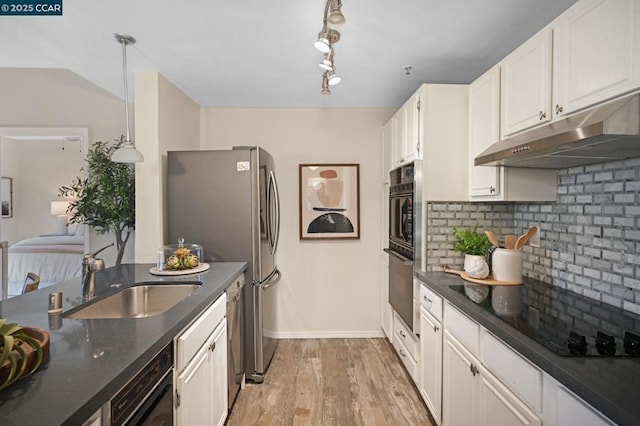 kitchen with pendant lighting, white cabinetry, tasteful backsplash, sink, and light wood-type flooring