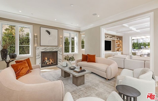 living room featuring a high end fireplace, built in shelves, crown molding, and coffered ceiling