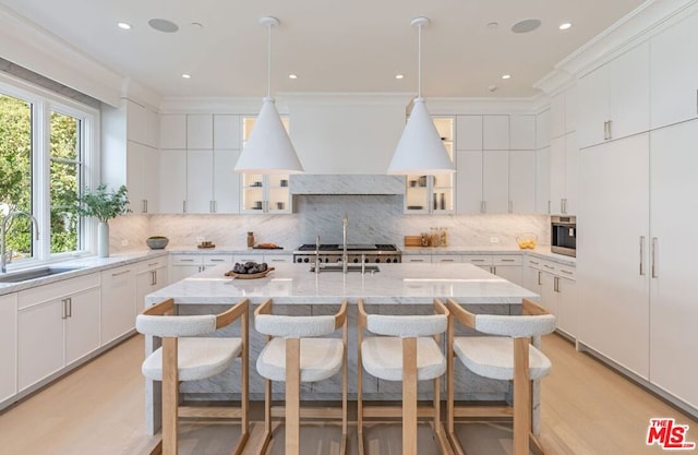 kitchen featuring a kitchen island, light stone countertops, hanging light fixtures, and sink