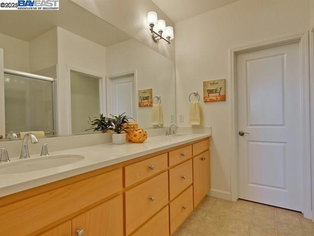 bathroom with walk in shower, vanity, and tile patterned floors