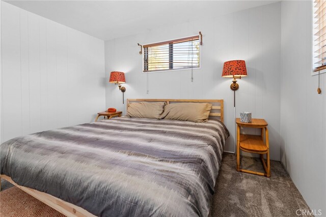 carpeted bedroom featuring wooden walls