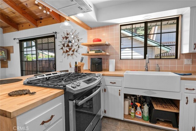 kitchen with wooden ceiling, gas stove, butcher block countertops, sink, and white cabinetry