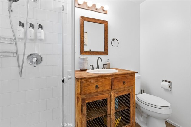 bathroom with toilet, vanity, and tiled shower