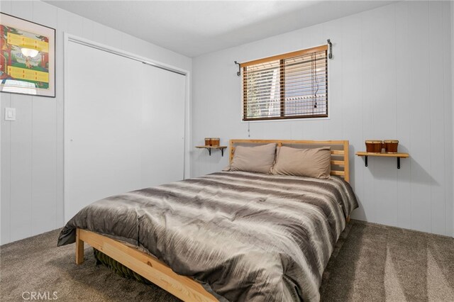 bedroom featuring wooden walls and carpet