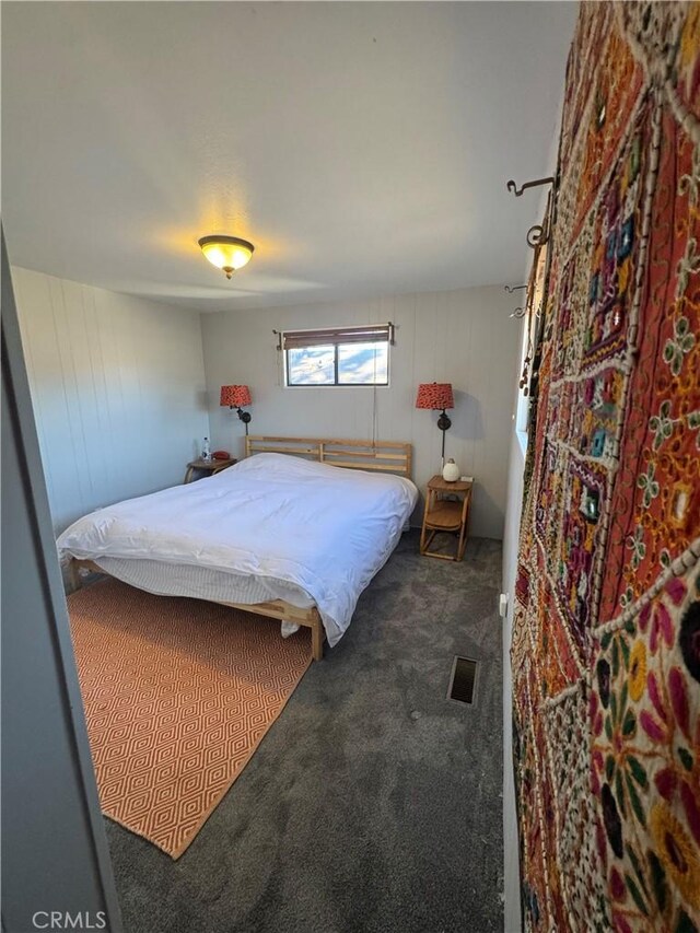 carpeted bedroom featuring wood walls