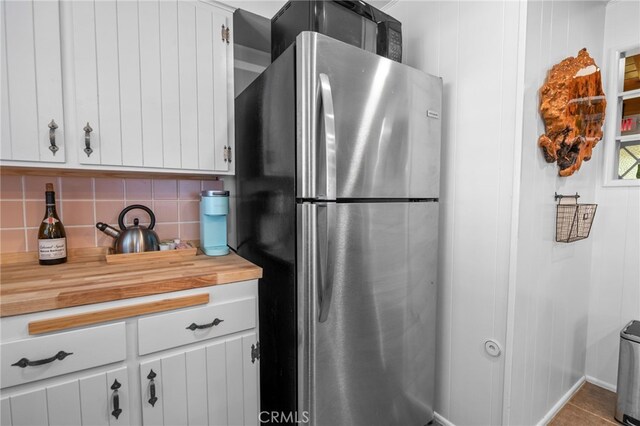 kitchen featuring white cabinets, stainless steel fridge, and tasteful backsplash