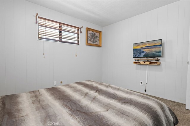 bedroom featuring wood walls and carpet floors