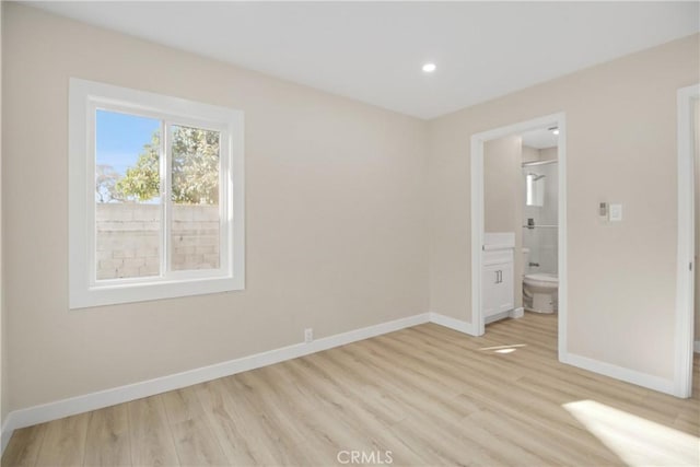 unfurnished bedroom featuring ensuite bath and light wood-type flooring