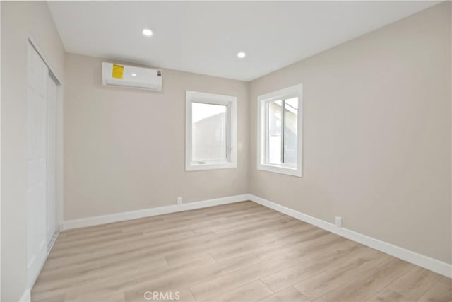 empty room featuring a wall unit AC and light hardwood / wood-style flooring