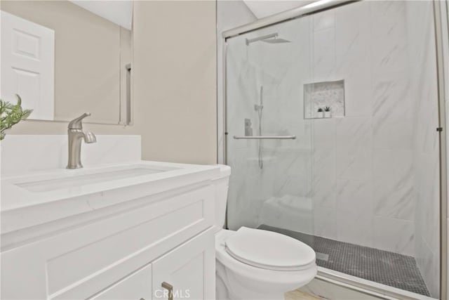 bathroom featuring toilet, a shower with shower door, and vanity