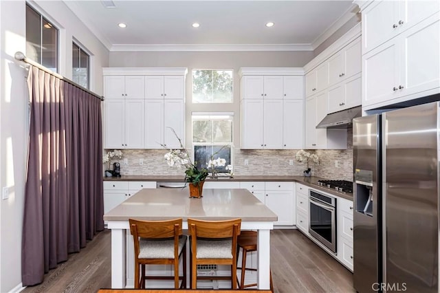 kitchen with a breakfast bar area, appliances with stainless steel finishes, white cabinets, and a center island