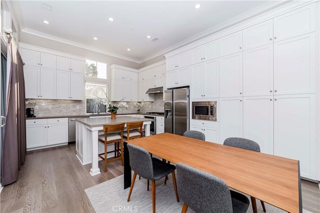 kitchen with white cabinets, a kitchen island, stainless steel appliances, sink, and light hardwood / wood-style flooring