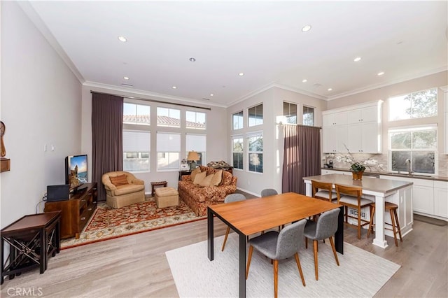 dining room featuring sink, crown molding, and light hardwood / wood-style floors