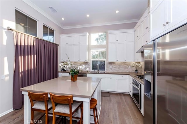 kitchen with white cabinets, appliances with stainless steel finishes, a center island, and a breakfast bar area