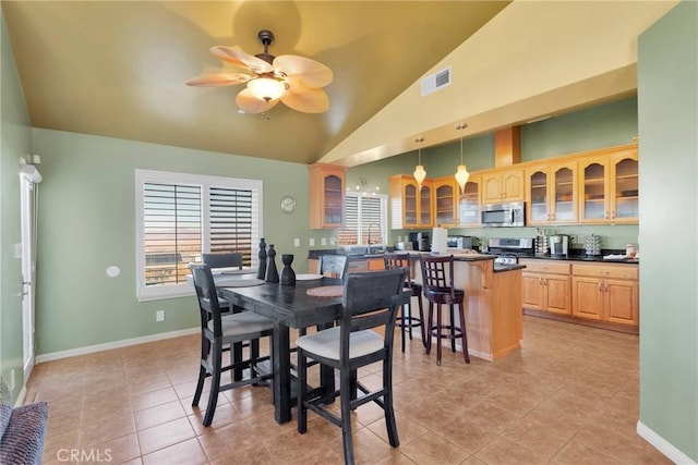 tiled dining space with ceiling fan and vaulted ceiling