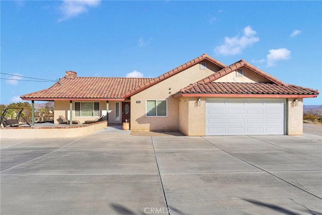 32758 Spinel Rd, Lucerne Valley, CA 92356 - mediterranean / spanish home with a tiled roof, a chimney, a garage, concrete driveway, and stucco siding