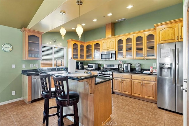 kitchen with light tile patterned floors, a kitchen island, appliances with stainless steel finishes, a kitchen breakfast bar, and sink