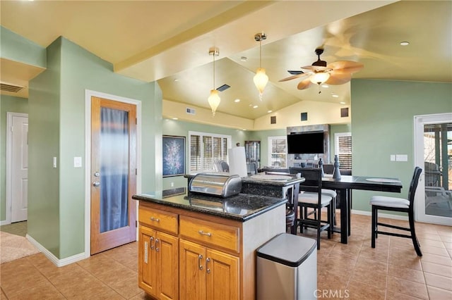 kitchen featuring a center island, dark stone counters, pendant lighting, ceiling fan, and lofted ceiling