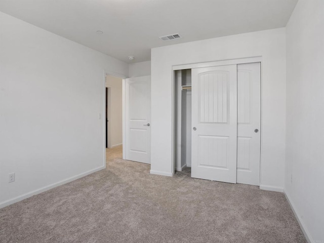 unfurnished bedroom with a closet and light carpet