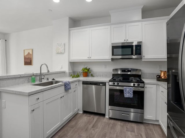 kitchen featuring sink, stainless steel appliances, light hardwood / wood-style floors, and white cabinets