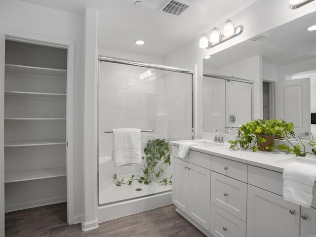 bathroom with hardwood / wood-style flooring, walk in shower, and vanity