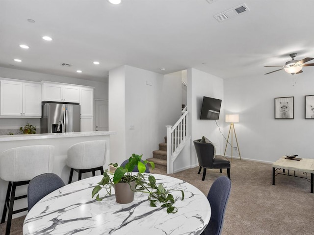 dining room with light colored carpet and ceiling fan