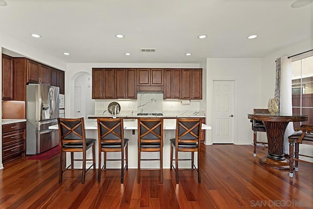 kitchen with stainless steel appliances, a center island with sink, and a kitchen bar