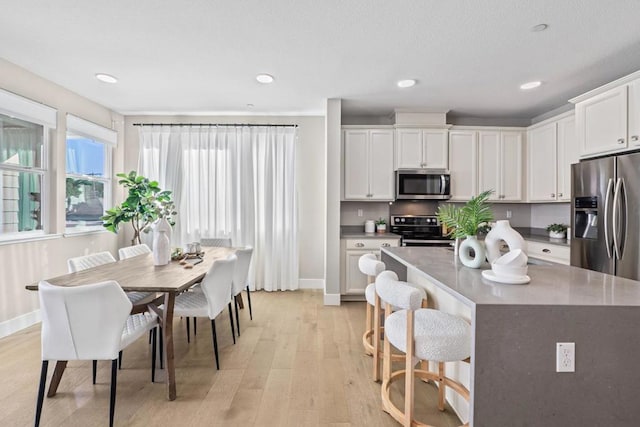 kitchen with white cabinets, a kitchen island, stainless steel appliances, and light hardwood / wood-style flooring