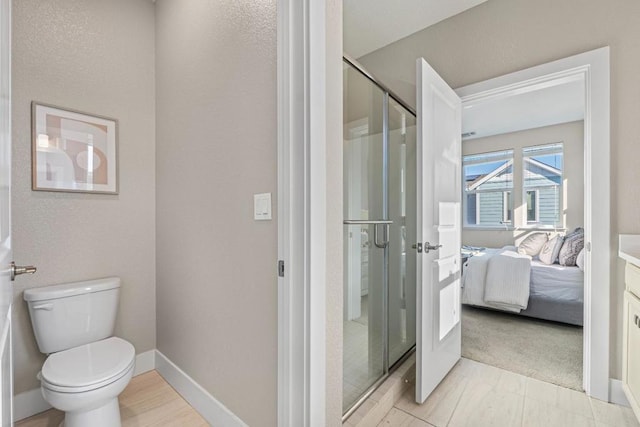 bathroom featuring toilet, vanity, and a shower with shower door