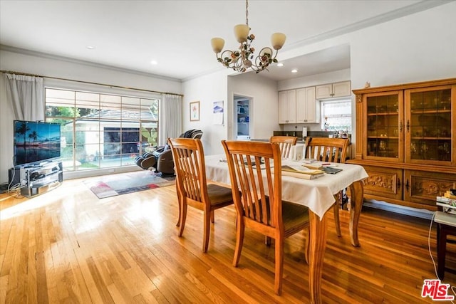 dining area featuring crown molding, light hardwood / wood-style floors, and a notable chandelier