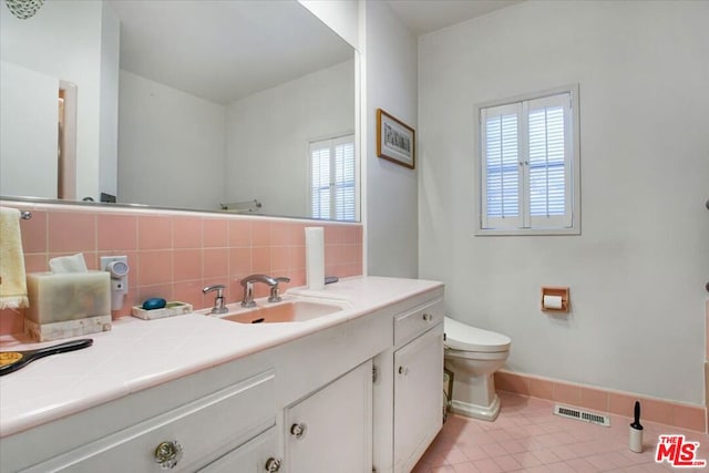 bathroom with toilet, vanity, tile patterned floors, and tasteful backsplash