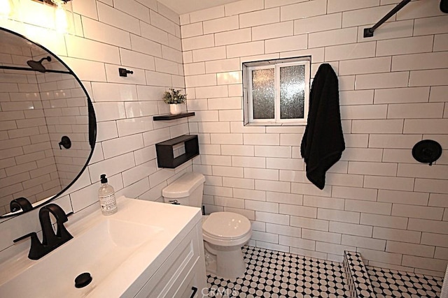 bathroom featuring toilet, a shower, tile walls, vanity, and tile patterned flooring