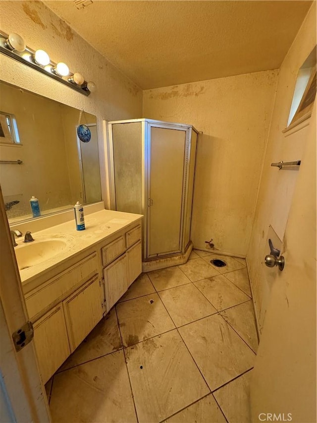 bathroom with a textured ceiling, a shower with door, tile patterned floors, and vanity