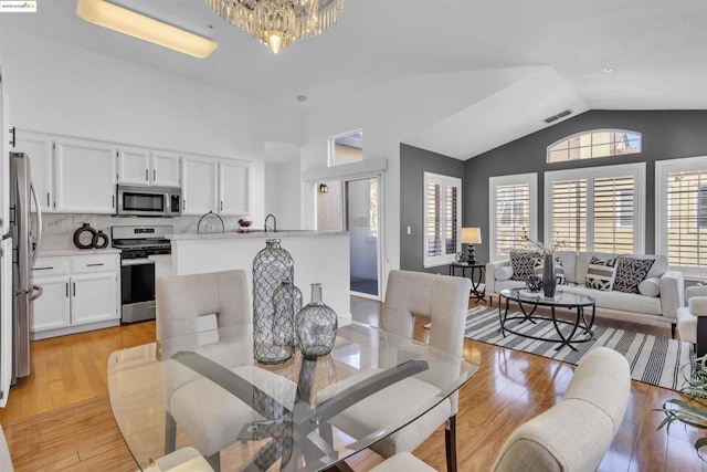 dining area featuring light hardwood / wood-style floors, lofted ceiling, and an inviting chandelier