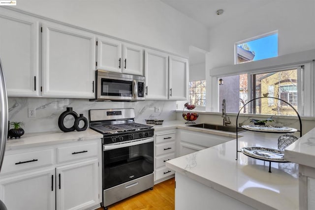 kitchen with backsplash, white cabinetry, and appliances with stainless steel finishes