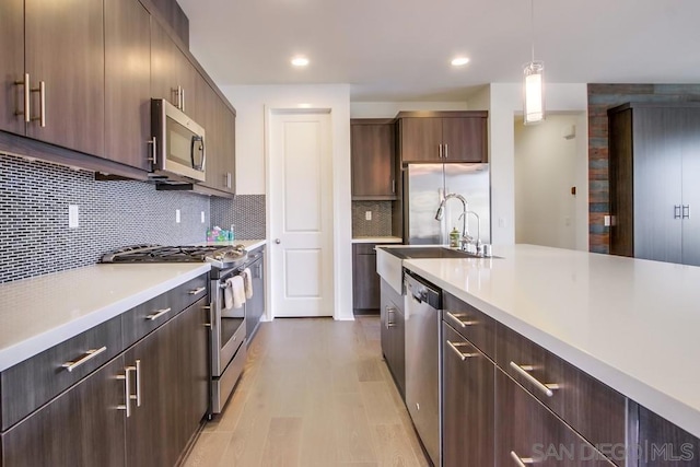 kitchen with stainless steel appliances, sink, tasteful backsplash, dark brown cabinets, and hanging light fixtures