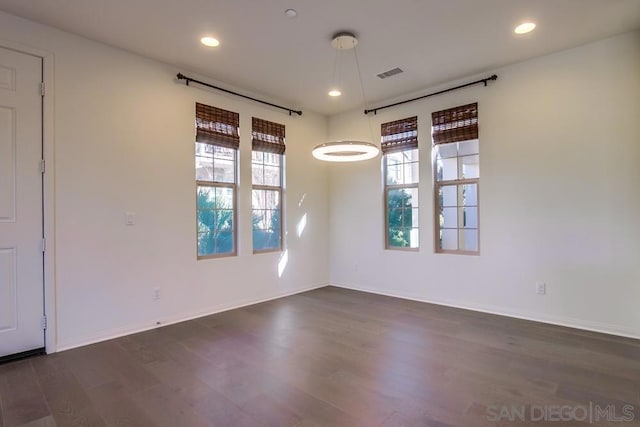 empty room with dark hardwood / wood-style floors and plenty of natural light