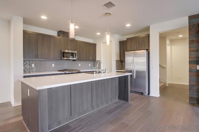 kitchen with hanging light fixtures, stainless steel appliances, dark hardwood / wood-style flooring, dark brown cabinets, and sink