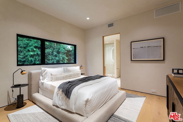 bedroom with ensuite bathroom and light hardwood / wood-style flooring