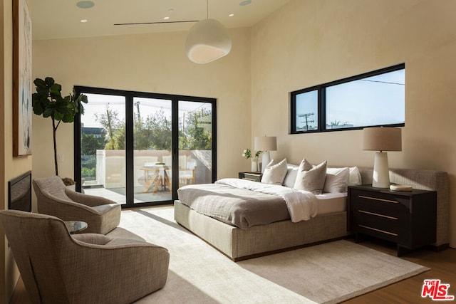 bedroom featuring lofted ceiling, access to outside, and light hardwood / wood-style flooring